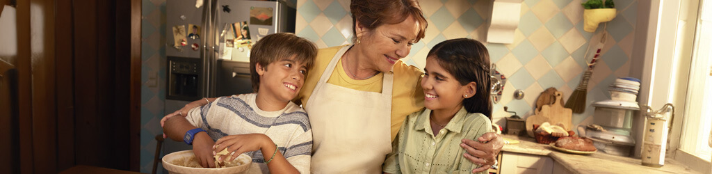 Nonna e nipoti abbracciati che cucinano sorridenti
